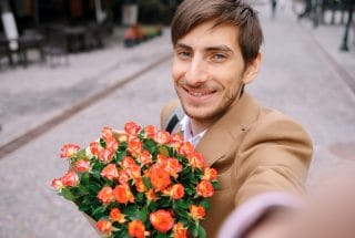 Smiling man making selfie with flowers