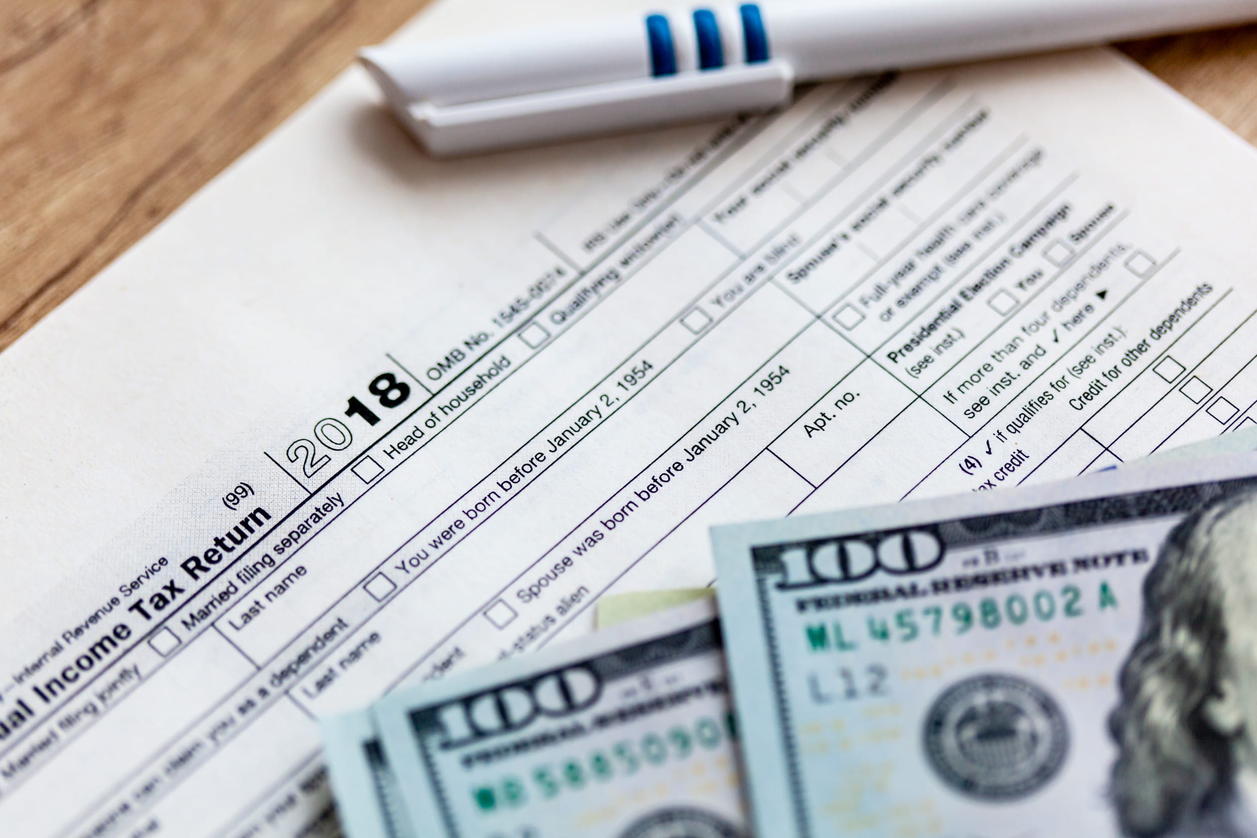 Someone who has filled out IRS forms with cash on top of them