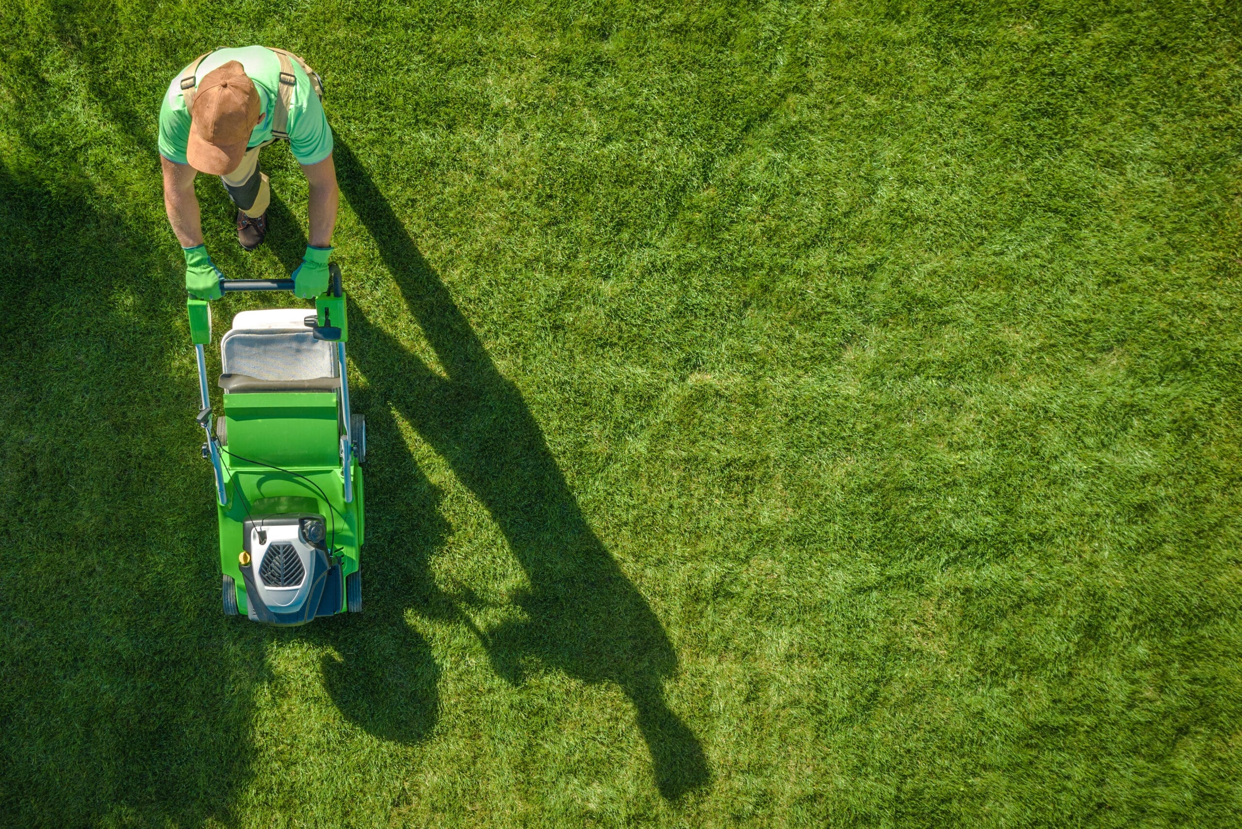 cost of lawn care -Lawn Moving Aerial Photo. Caucasian Gardener with Gasoline Grass Mower at Work. Landscaping Business. Industrial Theme.