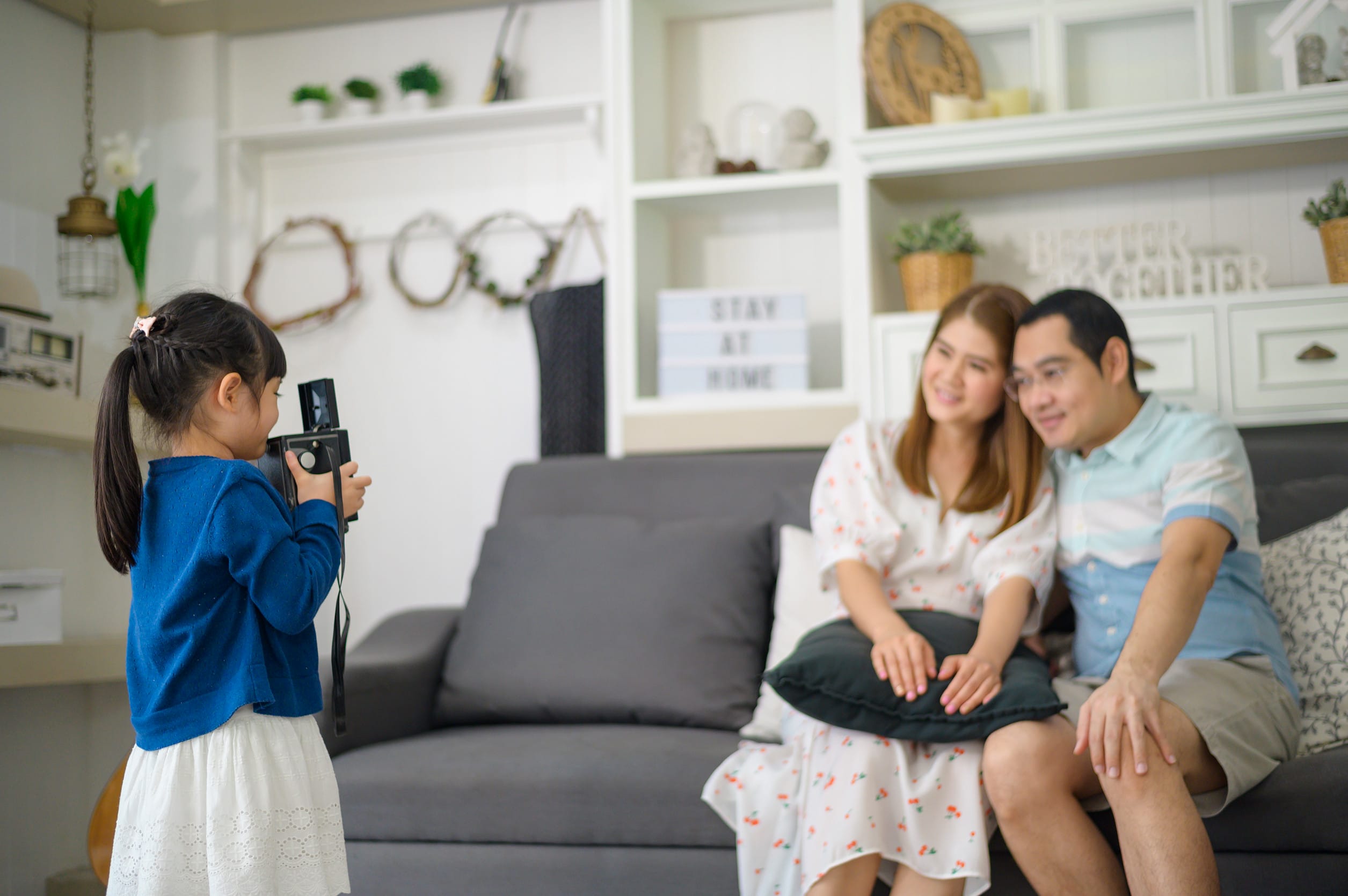 A young daughter taking a family photo of her happy parents