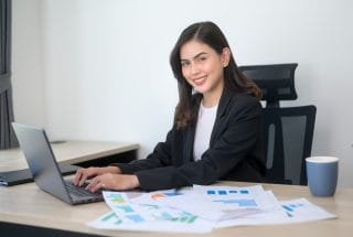 Young beautiful business woman working on laptop with documents in modern office
