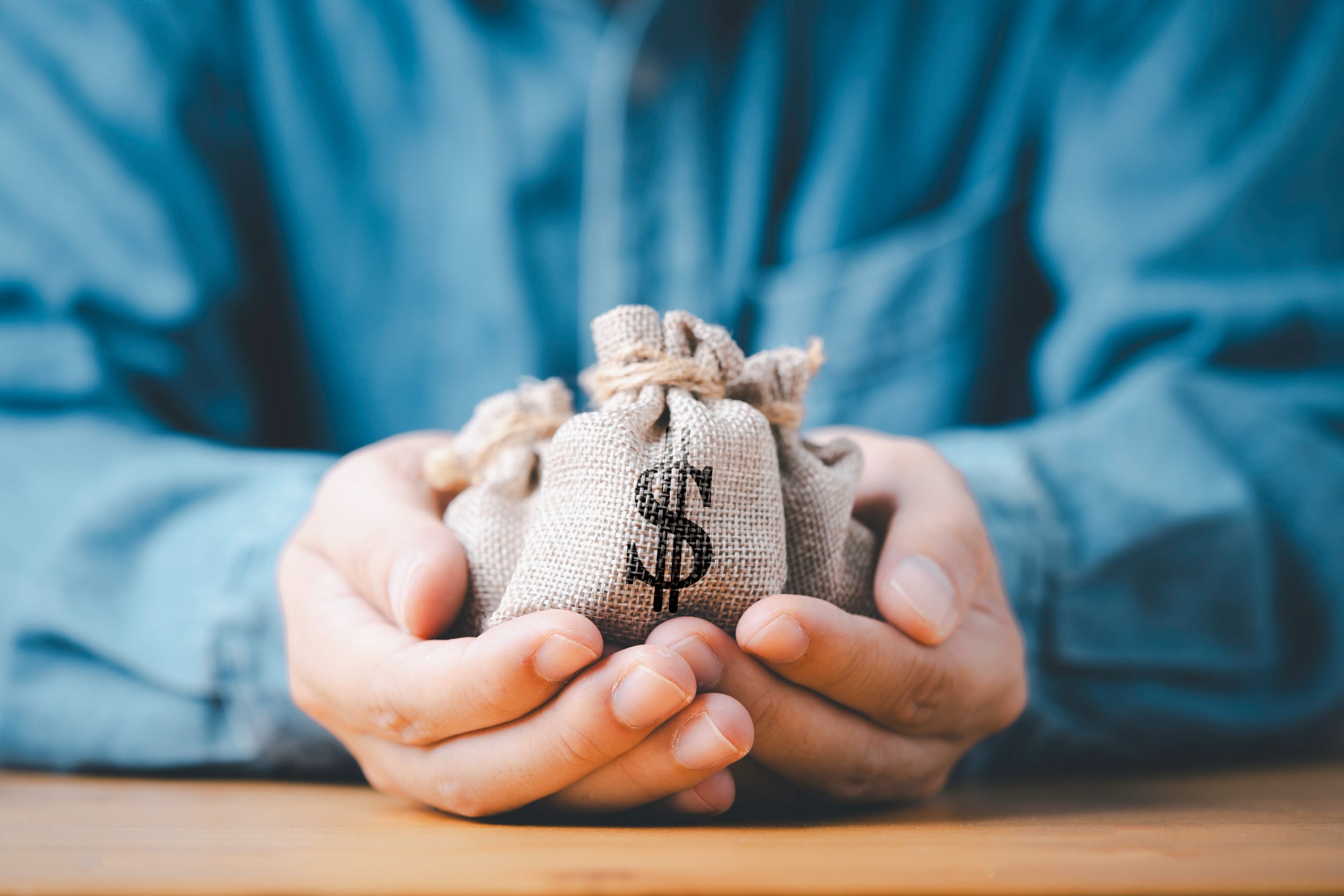 Someone holding bags of money, symbolizing their wealth
