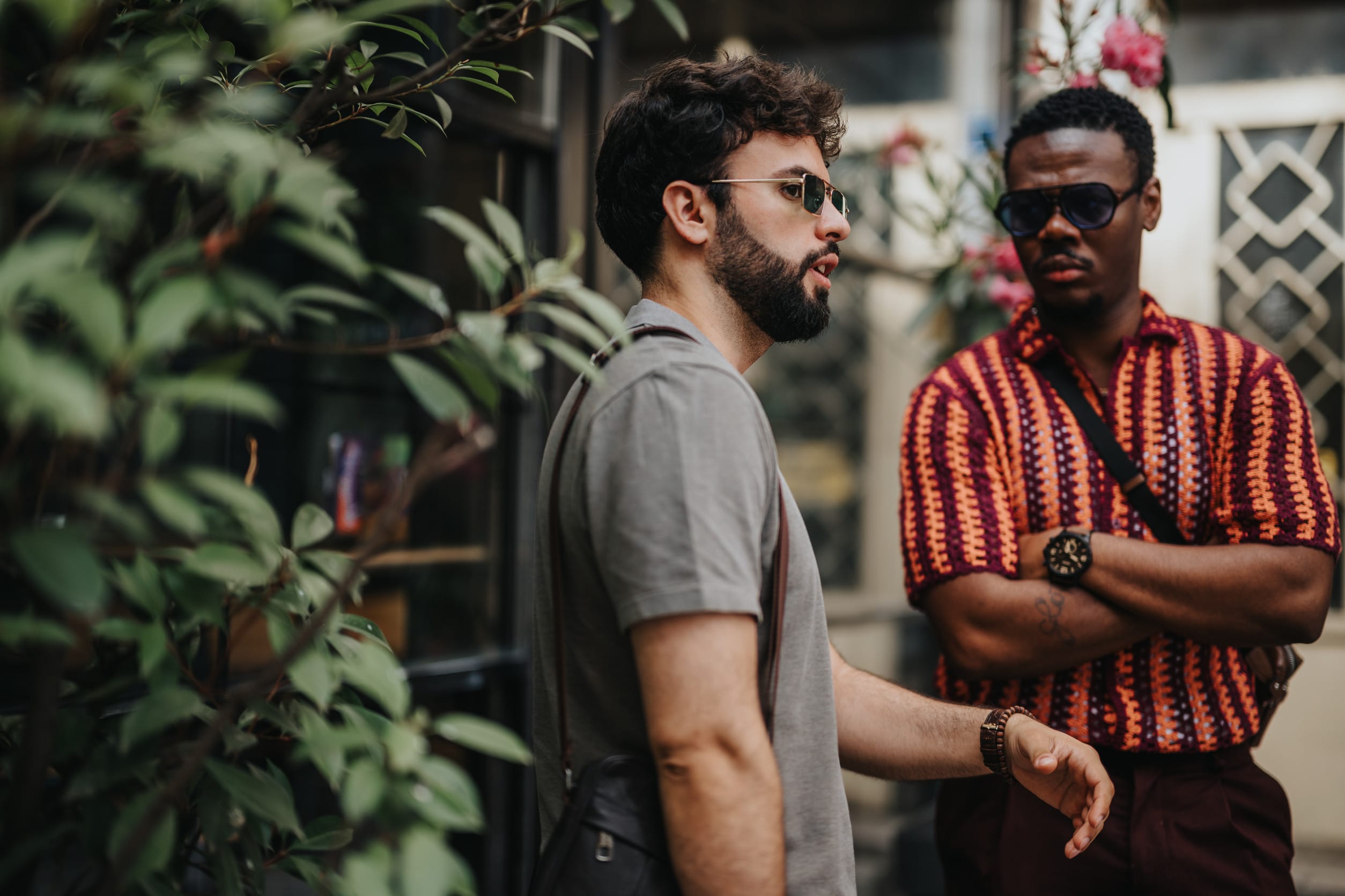Two businesspeople in casual discussion outdoors with sunglasses and colorful attire